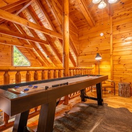 Challenge your travel companions to a friendly game in this inviting loft space, where soaring timber beams and warm wood finishes create a cozy mountain retreat vibe.