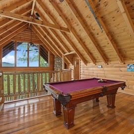 Your private game loft invites friendly competition beneath soaring cathedral ceilings, where warm wood and mountain views create the perfect backdrop for unforgettable evenings.