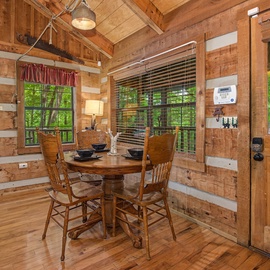 Step into your cozy cabin dining area with rustic charm and forest views just beyond the windows. Gather around the warm wood table and enjoy meals surrounded by nature.