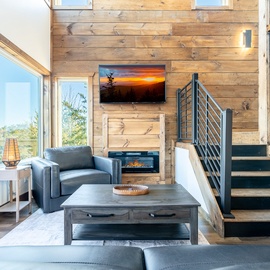 Unwind in your modern living space with cozy fireplace, sleek furnishings, and stunning views through floor-to-ceiling windows.