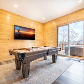 Your game room awaits with a premium pool table and arcade games, where cozy wood walls create the perfect atmosphere for friendly competition.