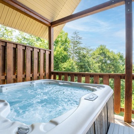 Soak in the bubbling hot tub on your private deck while gazing at lush mountain views—pure relaxation awaits under the covered canopy.