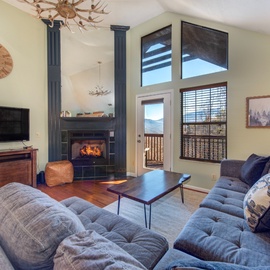 Cozy up in your spacious living room with soaring ceilings, crackling fireplace, and mountain views through expansive windows.