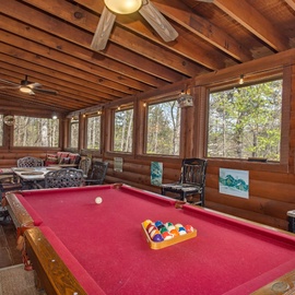 Your own rustic game area awaits with billiards, cozy seating, and forest views streaming through expansive windows.