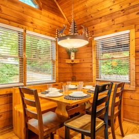Gather around this inviting dining table surrounded by warm wood and natural light—perfect for sharing meals and making memories during your stay.