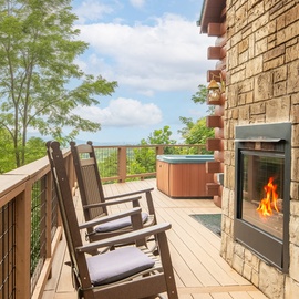 Relax in your rocking chair on this spacious deck, where a warm outdoor fireplace and hot tub await alongside sweeping views of lush forest. Pure mountain serenity.