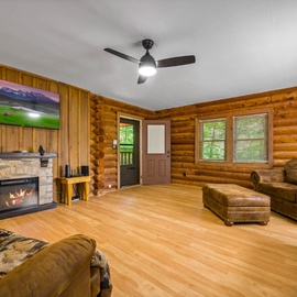 Cozy up in your rustic living room where warm wood walls and a crackling fireplace create the perfect mountain retreat atmosphere.