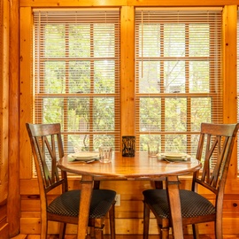 Gather around the warm wooden table and soak in peaceful forest views through sunlit windows—your tranquil spot for morning coffee or evening meals together.