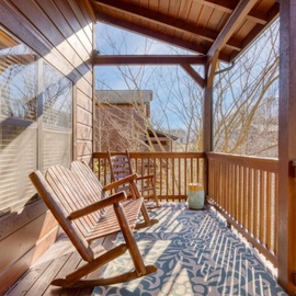 Settle into your private screened porch where wooden rockers invite peaceful moments surrounded by nature's quiet beauty.
