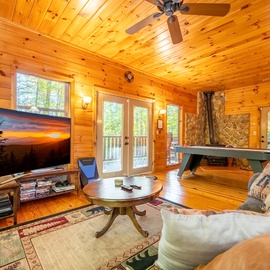 Step into a cozy cabin retreat where rustic pine walls surround your entertainment space, complete with French doors opening to your private deck and a billiard table for friendly competition.