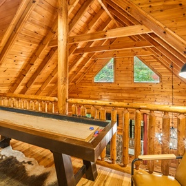 Gather around for friendly competition in your spacious loft game room, where soaring timber beams and warm pine walls create the perfect mountain hideaway atmosphere.