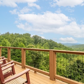 Sweeping mountain vistas stretch before you from this spacious deck, where classic Adirondack chairs invite quiet mornings and peaceful sunsets amid the fresh forest air.