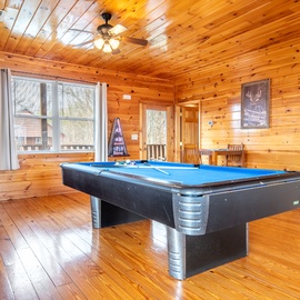 Challenge friends to pool games in this warm wooden cabin retreat with natural lighting and rustic charm.