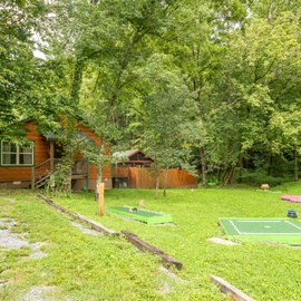A charming cabin nestled in the woods with miniature golf right outside your door, surrounded by towering trees and fresh mountain air.