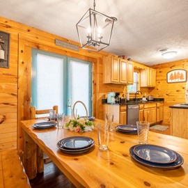 Gather around your private dining table in this warm, pine-clad kitchen—sunlight streams in as you savor meals together in rustic comfort.