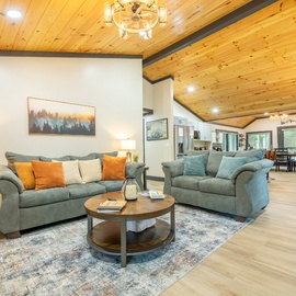Sink into plush sofas beneath a stunning knotty pine vaulted ceiling, where warm wood tones and soft lighting create your perfect mountain retreat atmosphere.