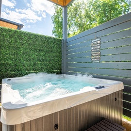 Slip into your private hot tub surrounded by lush greenery and privacy screens—picture yourself unwinding under the open sky with bubbles gently massaging away the day's stress.