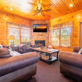 Sink into plush sofas before a crackling stone fireplace, surrounded by warm wood paneling and sunlight streaming through tall windows. Your cozy mountain retreat awaits.