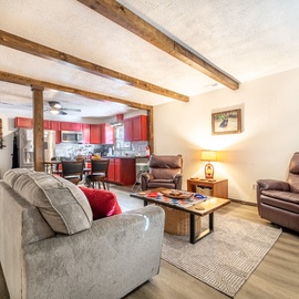Unwind in your spacious open-concept living area with exposed beams, where leather recliners and cozy seating invite you to relax after exploring.