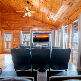 Relax in your cozy cabin theater room with warm wood walls, comfy leather seating, and stunning sunset views from the deck.