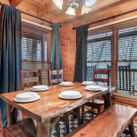 Gather around this handcrafted dining table where rustic wood walls and soft lighting create the perfect atmosphere for memorable meals together.