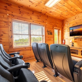 Settle into your own private theater with plush recliners and a stunning sunset view. This cozy cabin space invites you to unwind with movies under warm wood beams while natural light streams through.
