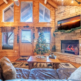 Cozy up by your crackling stone fireplace in this warm cabin living room, complete with festive Christmas tree and plush sofas.