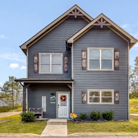 Love Gathers Us is nestled in a scenic hillside community, featuring a welcoming front entrance and natural landscaping that complements the surrounding wooded terrain.