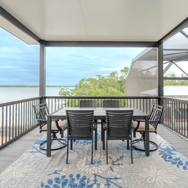 Your covered terrace offers perfect outdoor dining with stunning water views beyond the lush greenery.