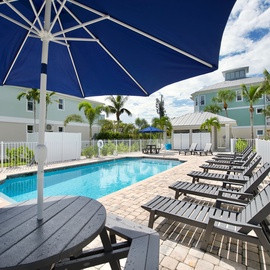 Community Pool with tables with umbrellas and lots of loungers