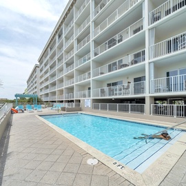 Take a refreshing dip in the community pool surrounded by swaying palms and white balconies, where coastal breezes and crystal-clear water create the perfect beachside retreat.