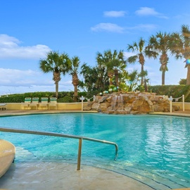 Dive into your tropical paradise with crystal-clear waters, a cascading rock waterfall, and swaying palms under endless blue skies.