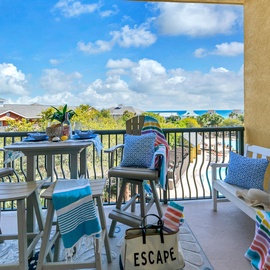 Relax on your private balcony with gulf views and dining space, overlooking a peaceful residential neighborhood under bright blue skies.