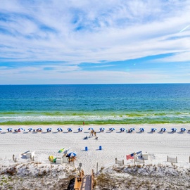 Pristine white sand beach with organized umbrellas and chairs stretching along the stunning Gulf Coast waters.