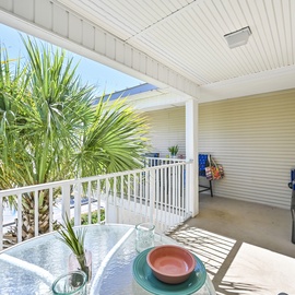 Sip your morning coffee on this peaceful covered balcony, where tropical palms frame your view and gentle breezes make every moment feel like paradise.