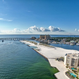 Aerial view of the stunning waterfront resort with pristine beaches, turquoise waters, and scenic bridge connecting to the community.