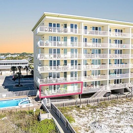 Multi-story beachfront property with white balconies overlooking the Gulf Coast, featuring swimming pool and beach boardwalk access.