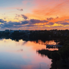 Stunning sunset paints the sky in brilliant oranges and purples over the peaceful lakefront community.