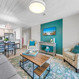 Relax in your bright, coastal-themed living space with turquoise accents and open kitchen—perfect for memorable vacation moments.