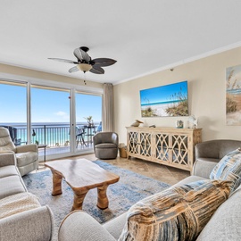 Your oceanfront living room features comfortable seating, ceiling fan, and stunning sea views through floor-to-ceiling windows.