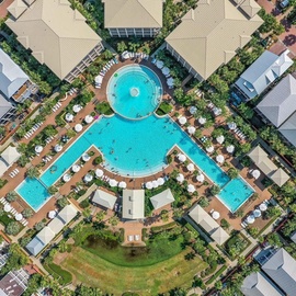 Aerial view showcasing the resort's expansive pool complex with multiple connected swimming areas surrounded by tropical landscaping and guest accommodations.