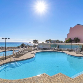 Beachfront resort pool with sparkling blue water and direct ocean access under sunny skies.