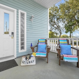 Your private entrance opens to a welcoming deck where colorful chairs invite you to unwind under mature trees.