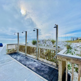 Beachfront boardwalk with outdoor showers overlooking pristine white sand and azure waters.