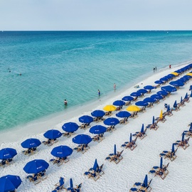 Pristine white sand beach with crystal-clear turquoise waters and organized umbrella service for ultimate relaxation.