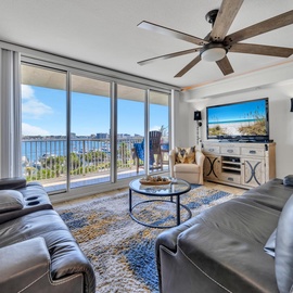 Relax in your waterfront living room where stunning harbor views stretch beyond floor-to-ceiling windows, creating the perfect backdrop for your coastal getaway.