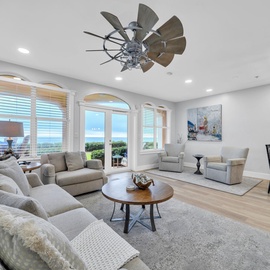 Relax in your bright living room with plush seating and ocean views through elegant French doors.