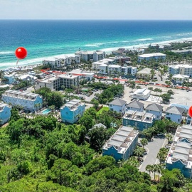 Aerial view of coastal vacation rental properties nestled among lush trees, just minutes from pristine turquoise waters and white sand beaches.