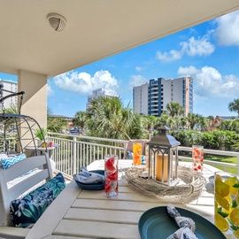 Your private balcony offers the perfect tropical retreat with a cozy hanging chair and beautifully set dining table overlooking palm trees.