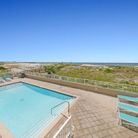 Beachfront pool deck with stunning ocean views and direct beach access beyond natural dunes.